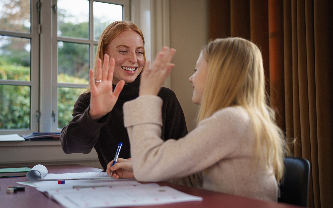 Underviser og elev gir hverandre high five
